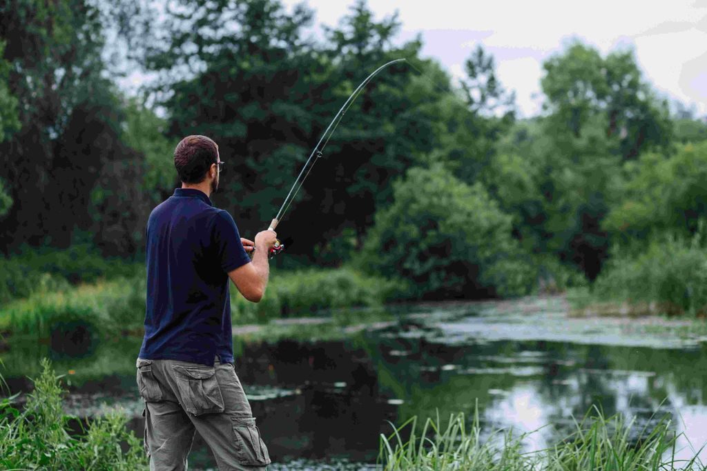 Jrebchevo Dam, Bulgaria a man caught fish on the fishing line trying to get  it out on the shore. Stock Photo